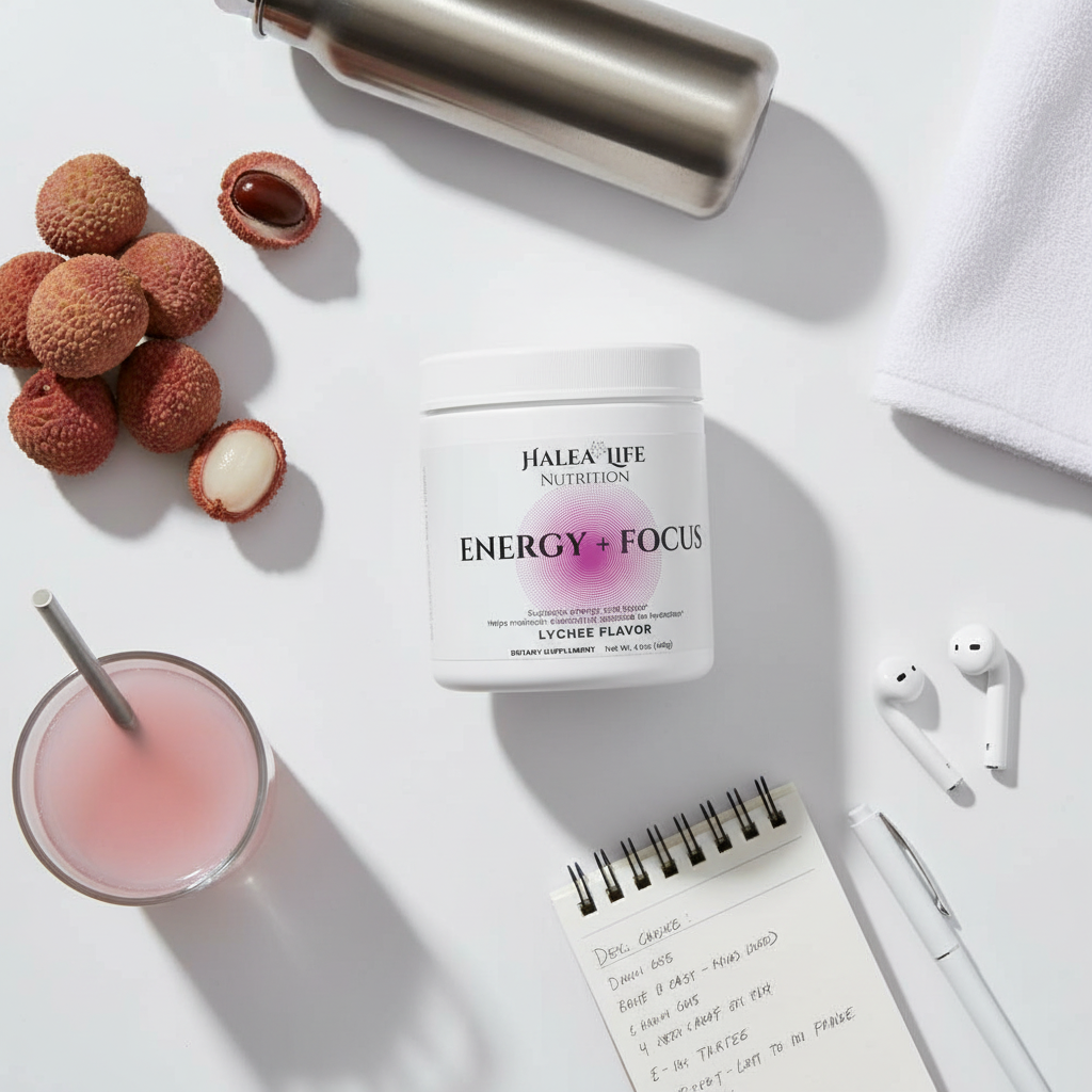 Halea Life Energy + Focus supplement container with lychees, a glass of pink drink, and earbuds on a white surface.