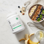 Halea Life plant-based protein container with a bowl of granola, fruit, and a whisk on a light surface.